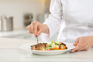 Professional chef decorating delicious dish with thyme at marble table, closeup. Space for text