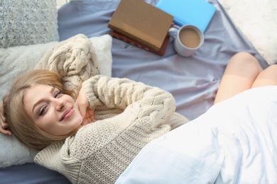 Beautiful young woman awaking and smiling at home, top view. Winter atmosphere