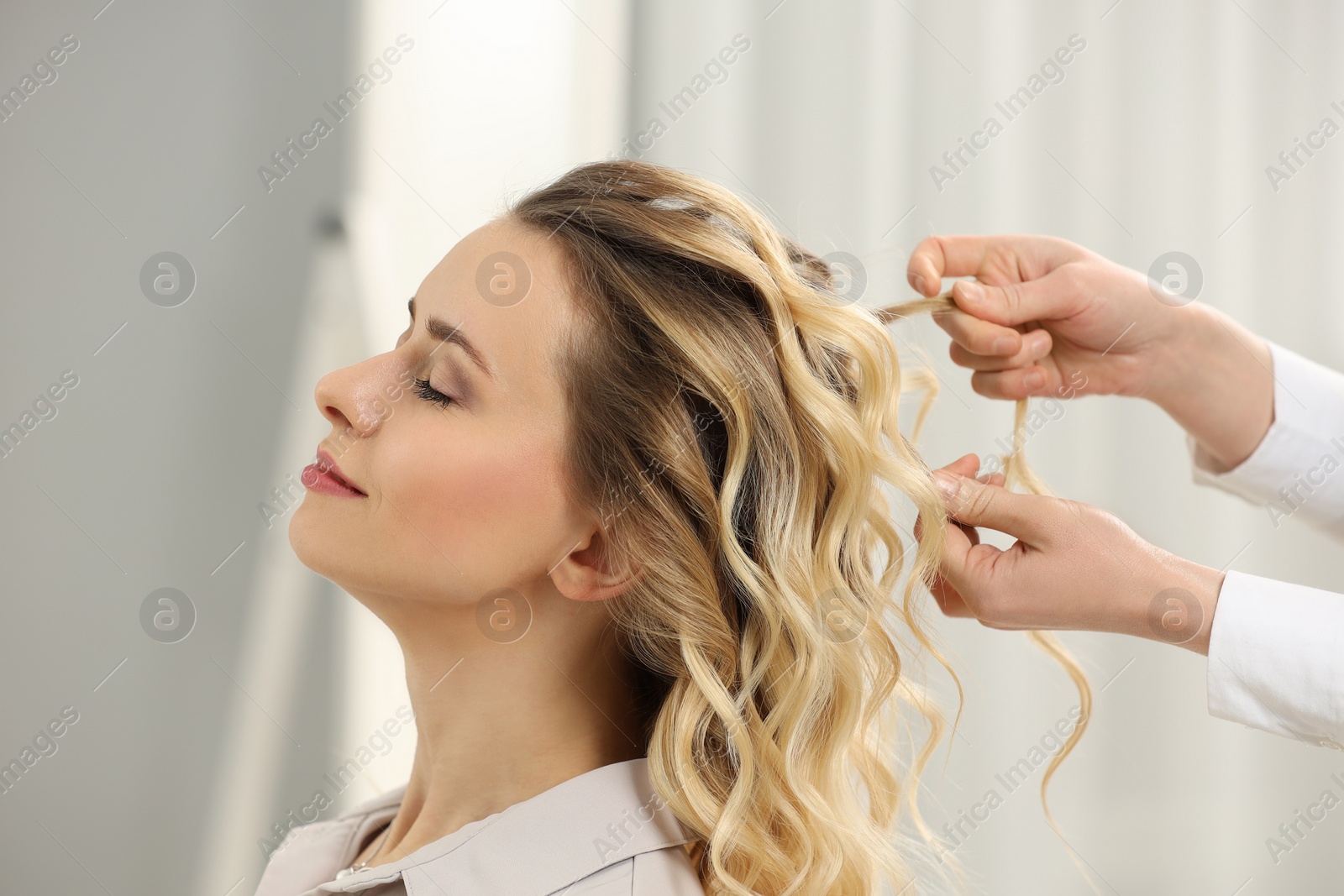 Photo of Hair styling. Professional hairdresser working with client indoors, closeup