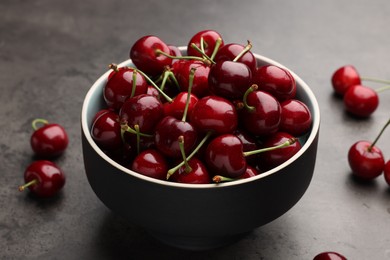 Photo of Bowl with ripe sweet cherries on grey table, closeup