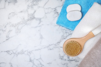 Photo of Fresh towels, brush and spa stones on white marble table, flat lay. Space for text