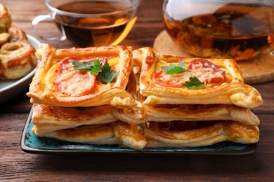 Photo of Fresh delicious puff pastry with cheese, tomatoes and parsley on wooden table, closeup