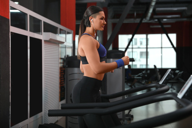 Photo of Young woman working out on treadmill in modern gym