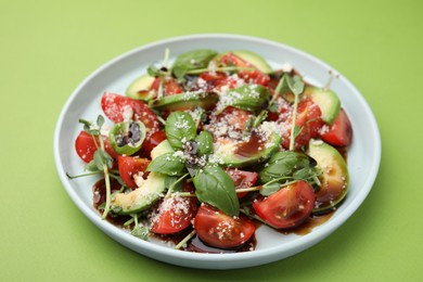 Photo of Tasty salad with balsamic vinegar on light green background