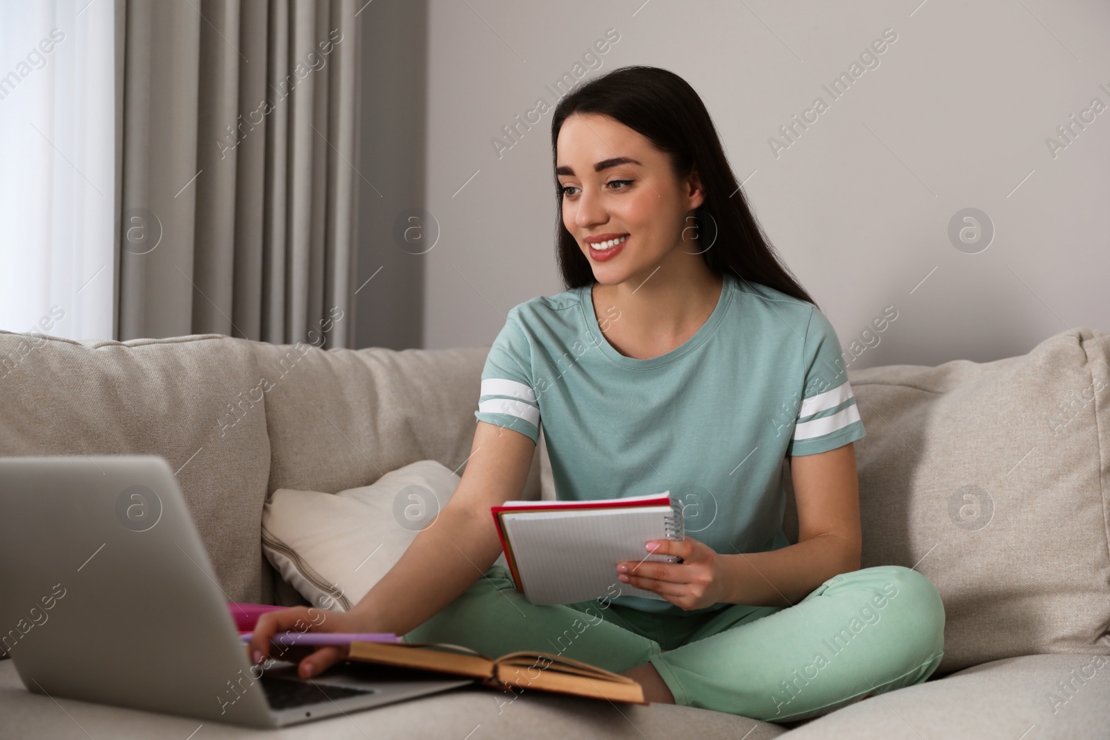 Photo of Young woman watching webinar on sofa at home