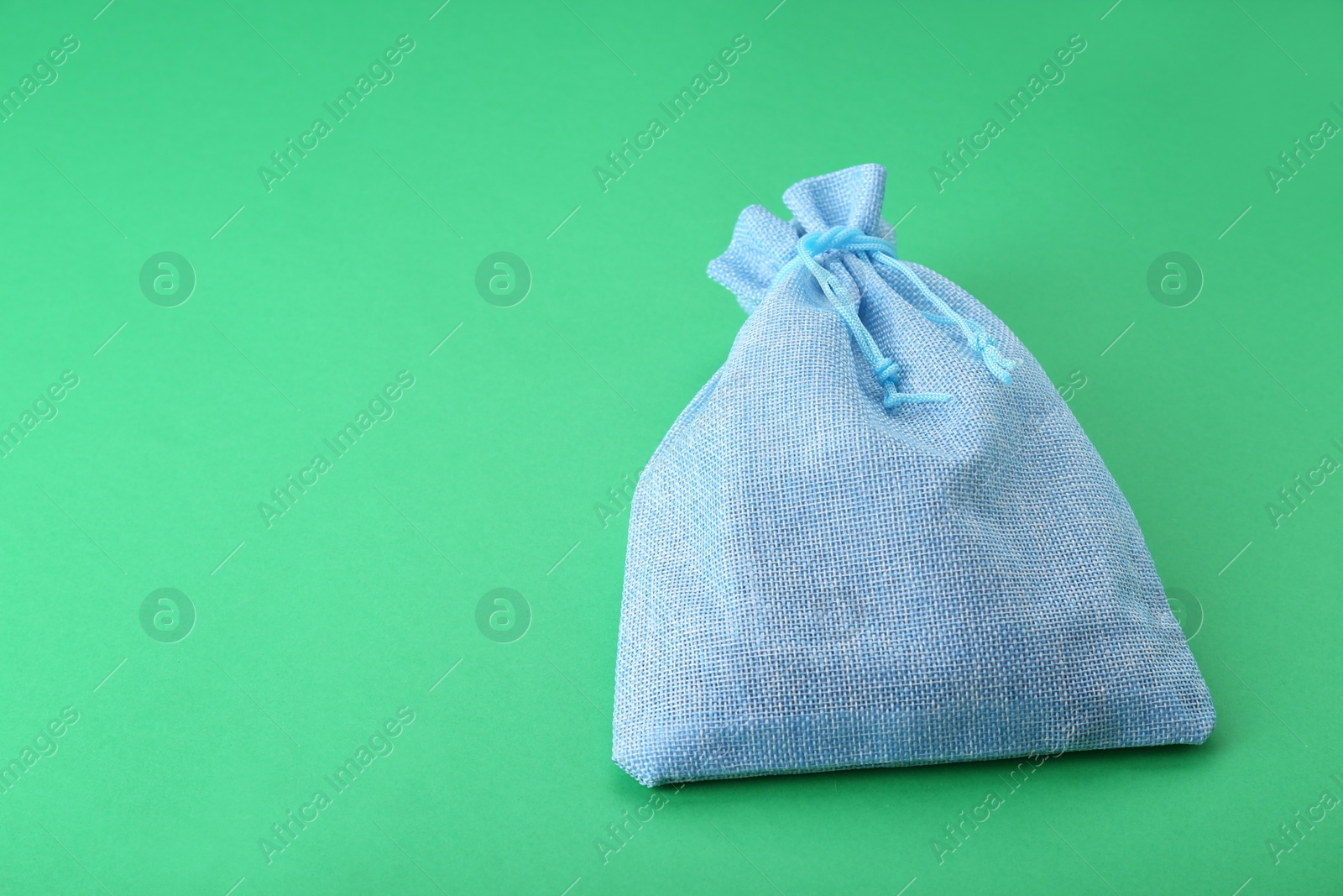 Photo of Tied burlap bag on green background. Space for text