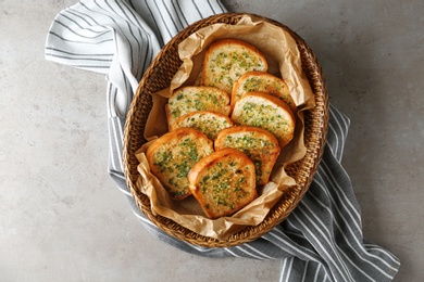 Photo of Slices of toasted bread with garlic and herbs on grey table, top view