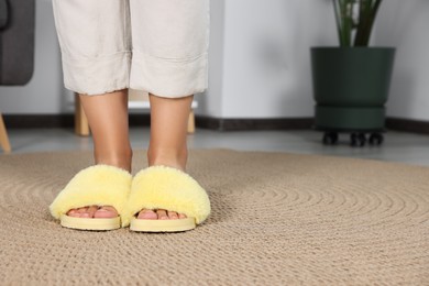 Photo of Woman wearing soft slippers at home, closeup of legs