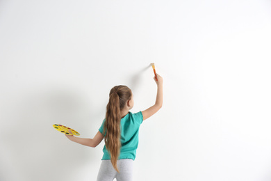 Photo of Little child painting on white wall indoors