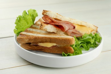 Photo of Tasty sandwiches with ham, lettuce and melted cheese on white wooden table, closeup