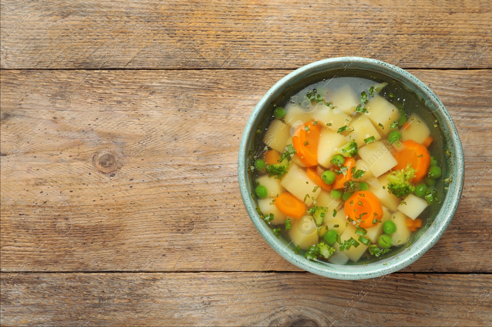 Photo of Bowl of fresh homemade vegetable soup on wooden background, top view. Space for text