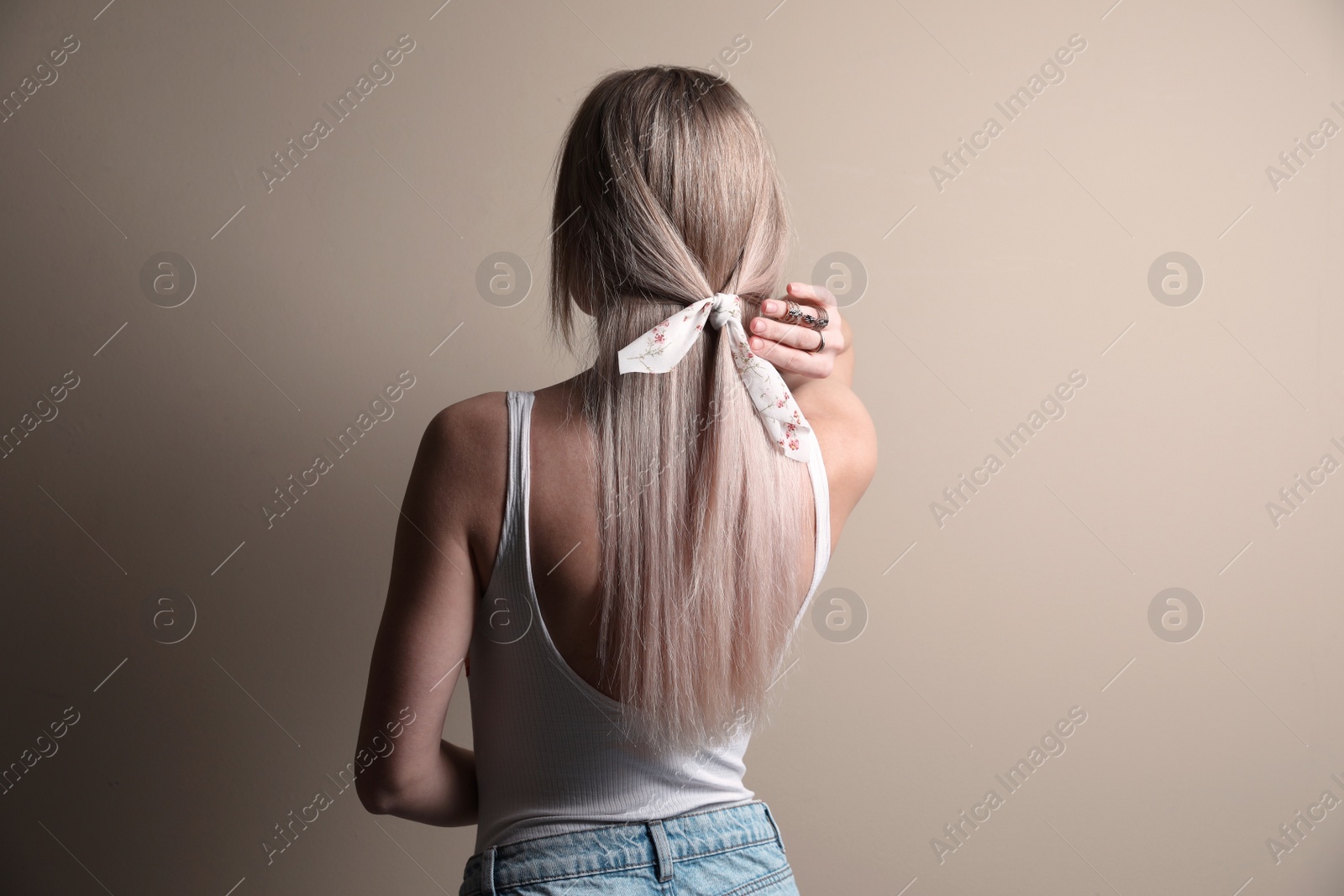 Photo of Young woman with stylish bandana on beige background, back view