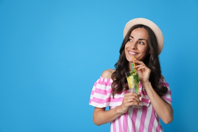 Young woman with refreshing drink on blue background. Space for text