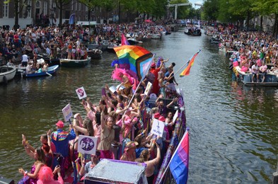 Photo of AMSTERDAM, NETHERLANDS - AUGUST 06, 2022: Many people in boats at LGBT pride parade on river