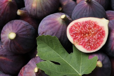 Photo of Fresh ripe figs and green leaf as background, closeup