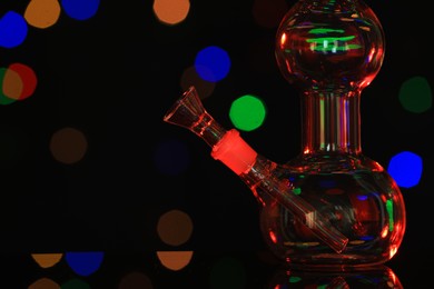 Closeup view of glass bong against blurred lights. Smoking device