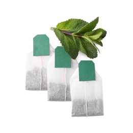 Photo of New tea bags with labels and mint on white background, top view