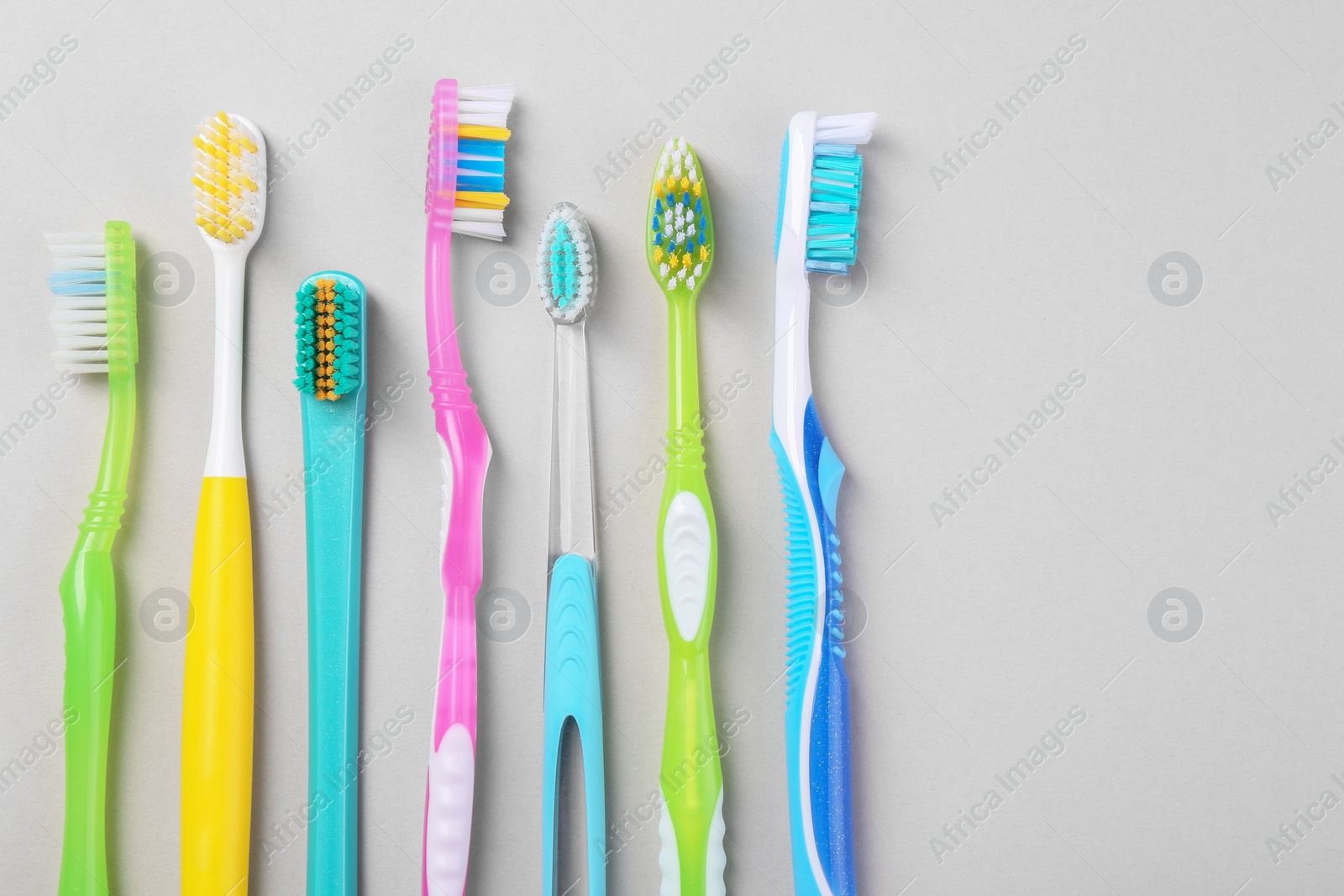 Photo of Many different toothbrushes on light background, flat lay. Space for text