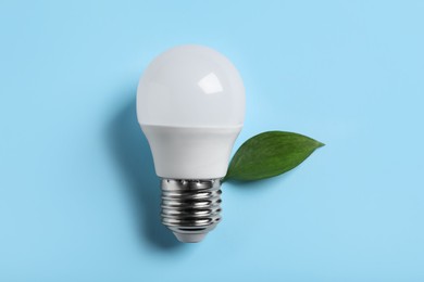 Photo of Light bulb and green leaf on color background, flat lay