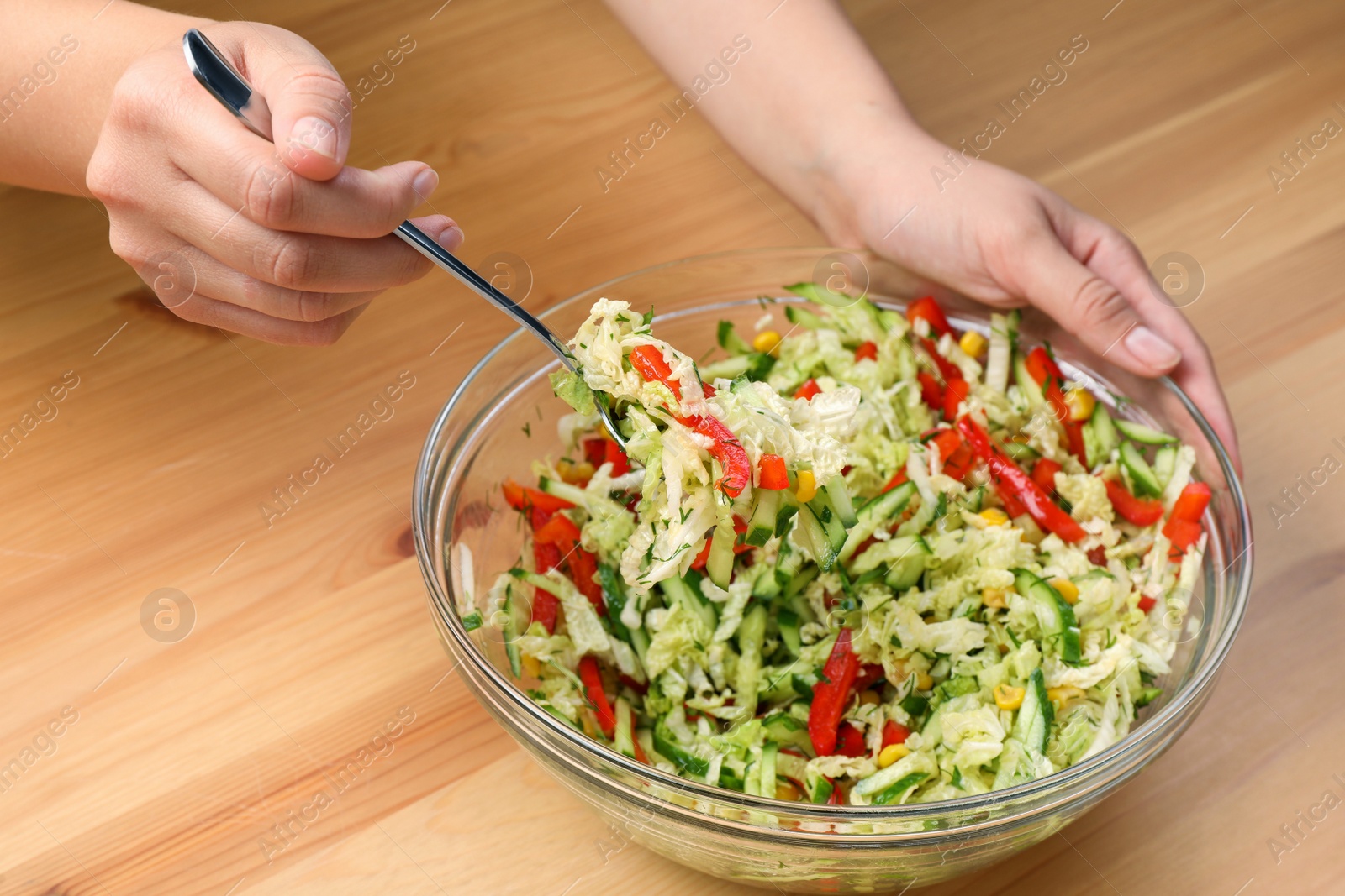 Photo of Woman making tasty salad with Chinese cabbage at wooden table, closeup