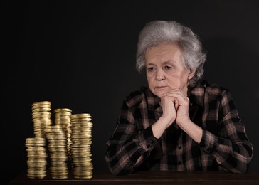 Pension plan. Senior woman and stacks of coins on black background