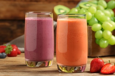 Glasses with different tasty smoothies and ingredients on wooden table