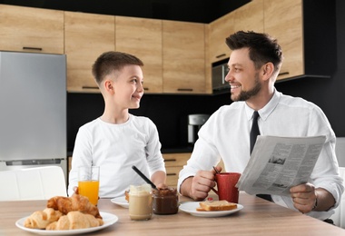 Dad and son having breakfast together in kitchen