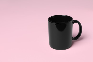 Photo of One black ceramic mug on pink background, space for text