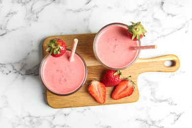 Photo of Tasty strawberry smoothies in glasses on white marble table, top view