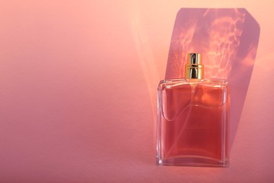 Photo of Luxury women's perfume in bottle on pale pink background, top view. Space for text