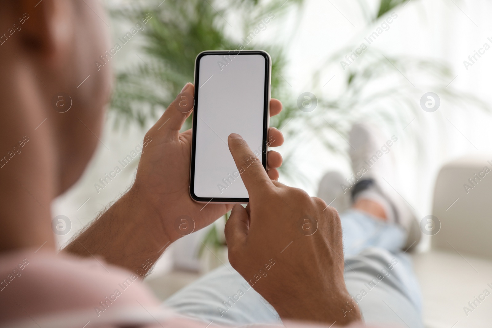 Photo of Man using mobile phone with empty screen indoors, closeup