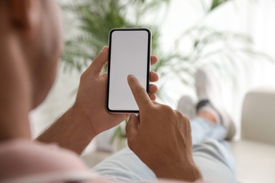 Photo of Man using mobile phone with empty screen indoors, closeup