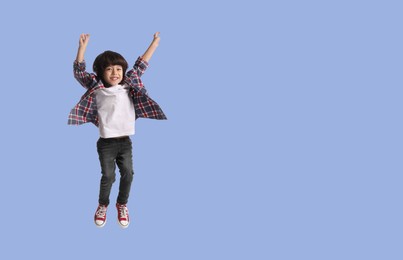 Image of Happy boy jumping on light blue background, space for text