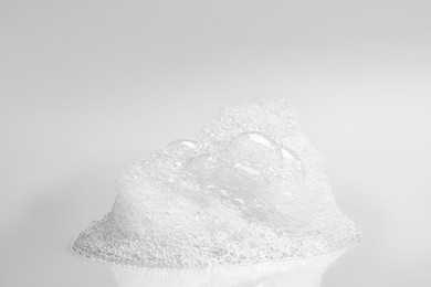 Photo of Drop of fluffy bath foam on light background