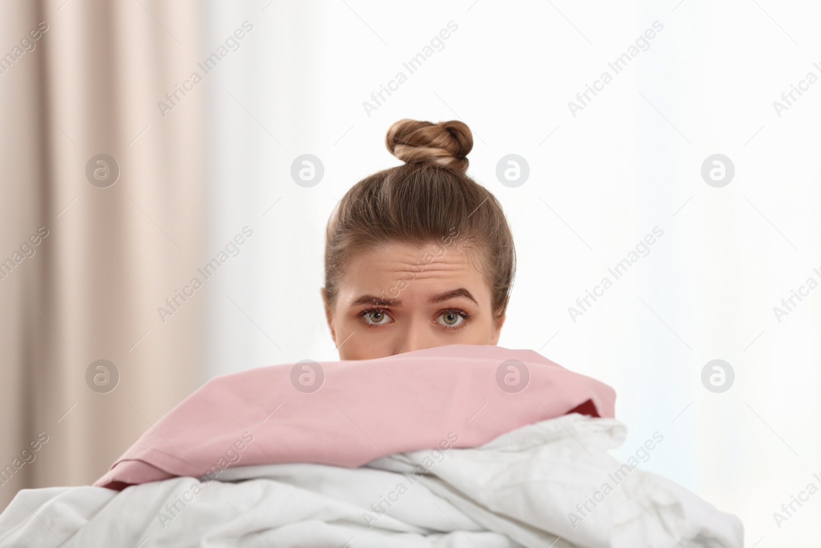 Photo of Woman holding pile of dirty laundry indoors