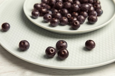 Photo of Plates with fresh acai berries on table, closeup