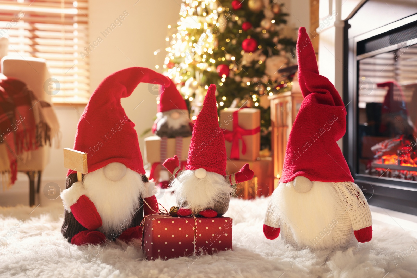 Photo of Cute Christmas gnomes and gift in room with festive decorations