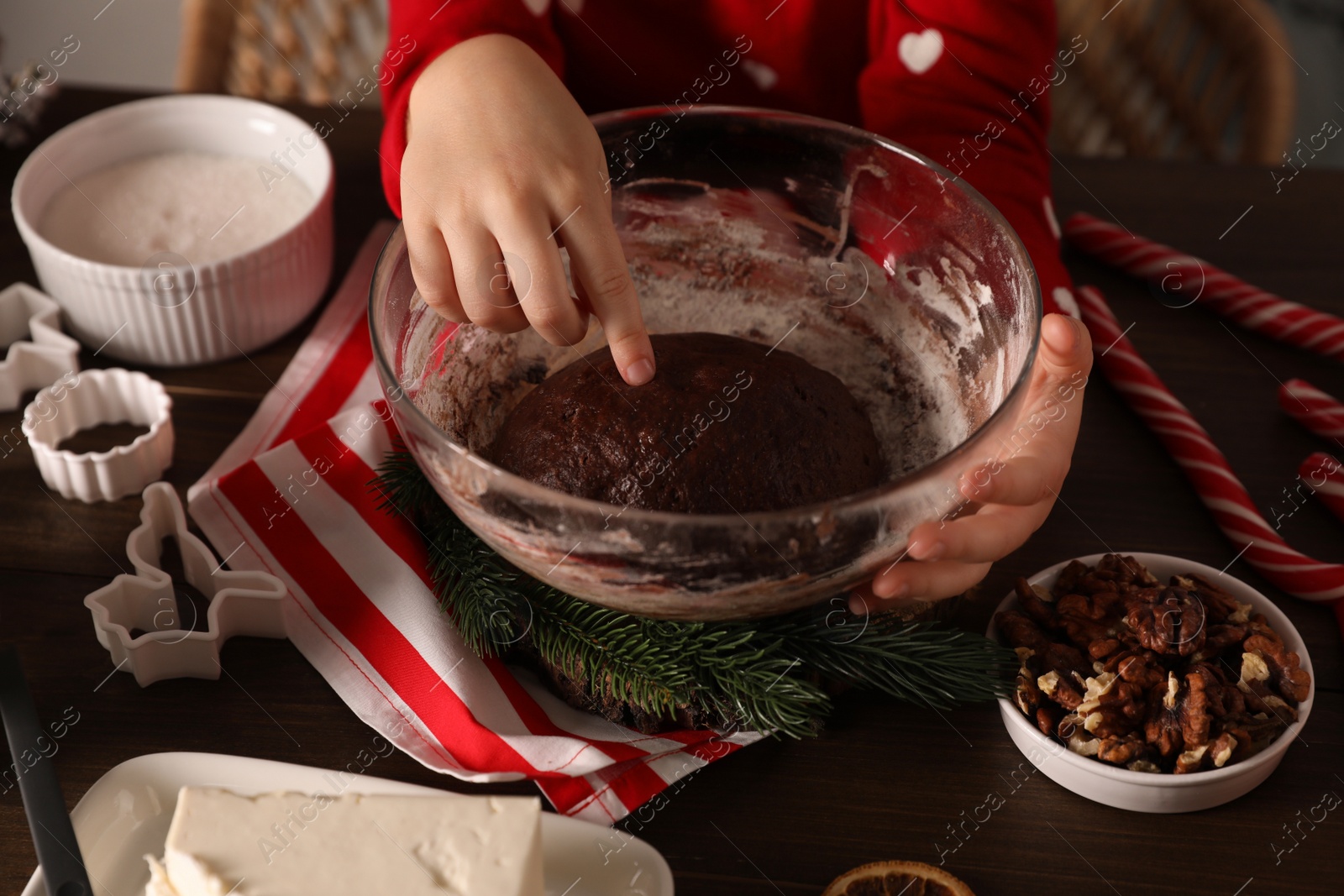 Photo of Little child making Christmas cookies at wooden table, closeup