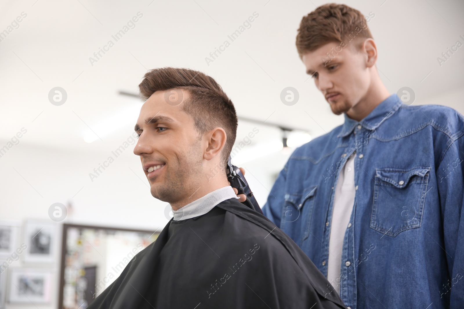 Photo of Professional barber working with client in hairdressing salon. Hipster fashion