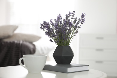 Photo of Beautiful lavender flowers, cup of coffee and book on white table indoors