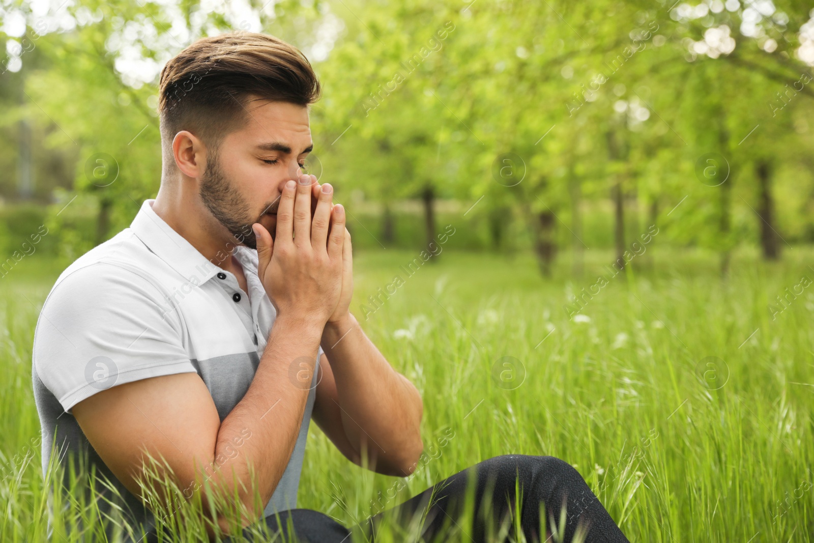 Photo of Young man suffering from seasonal allergy outdoors on sunny day, space for text