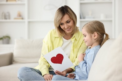 Photo of Little daughter congratulating her mom with greeting card at home, space for text. Happy Mother's Day