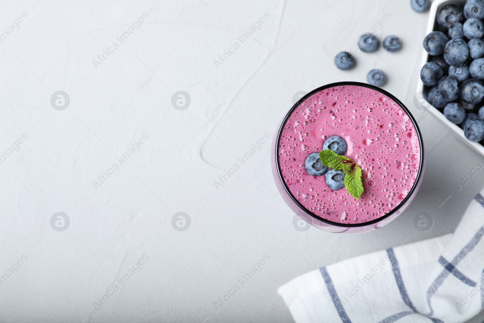 Photo of Flat lay composition with glass of tasty blueberry smoothie on grey table. Space for text