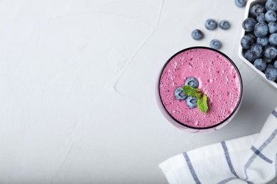 Photo of Flat lay composition with glass of tasty blueberry smoothie on grey table. Space for text