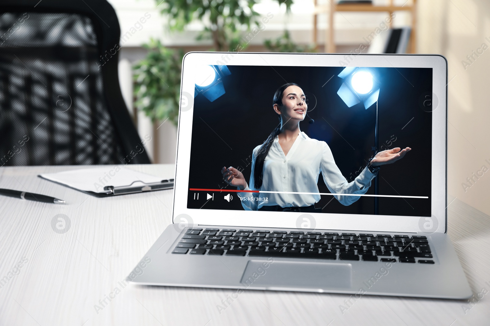 Image of Laptop with performance of motivational speaker on white table indoors