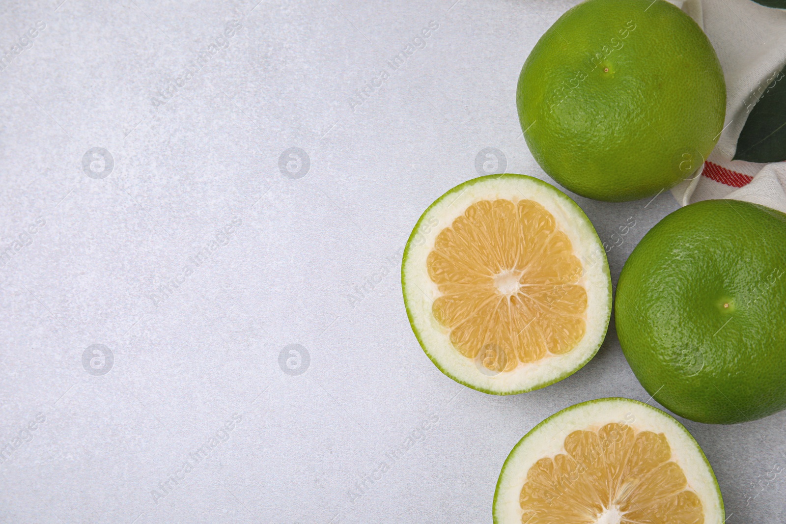 Photo of Whole and cut sweetie fruits on light table, flat lay. Space for text