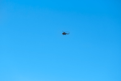 Photo of Modern military helicopter flying in blue sky