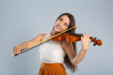 Photo of Beautiful woman playing violin on grey background