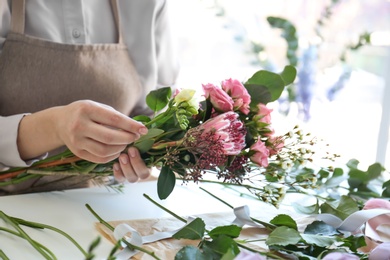 Photo of Female florist creating beautiful bouquet at table