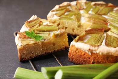 Photo of Freshly baked rhubarb pie and stalks on black table, closeup